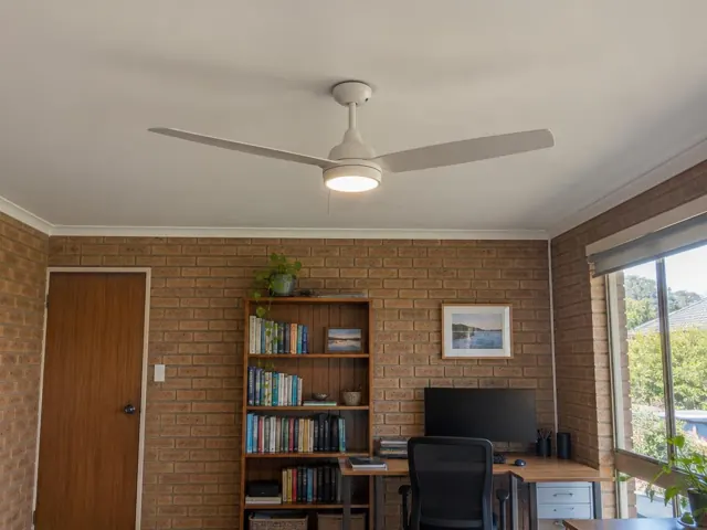 White ceiling fan on a painted ceiling above a brick-walled home office in The Entrance
