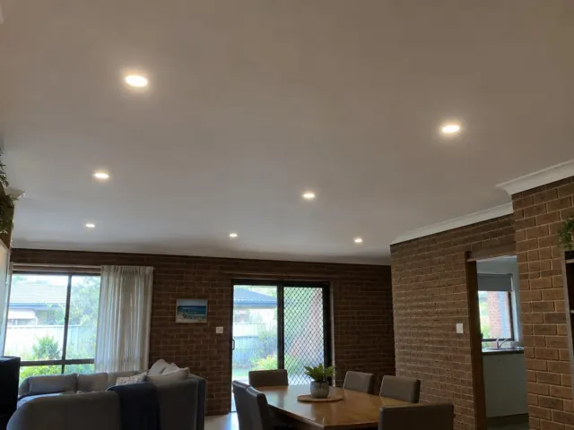 Living room ceiling with recessed LED downlights above brick walls and dining area in Norah Head